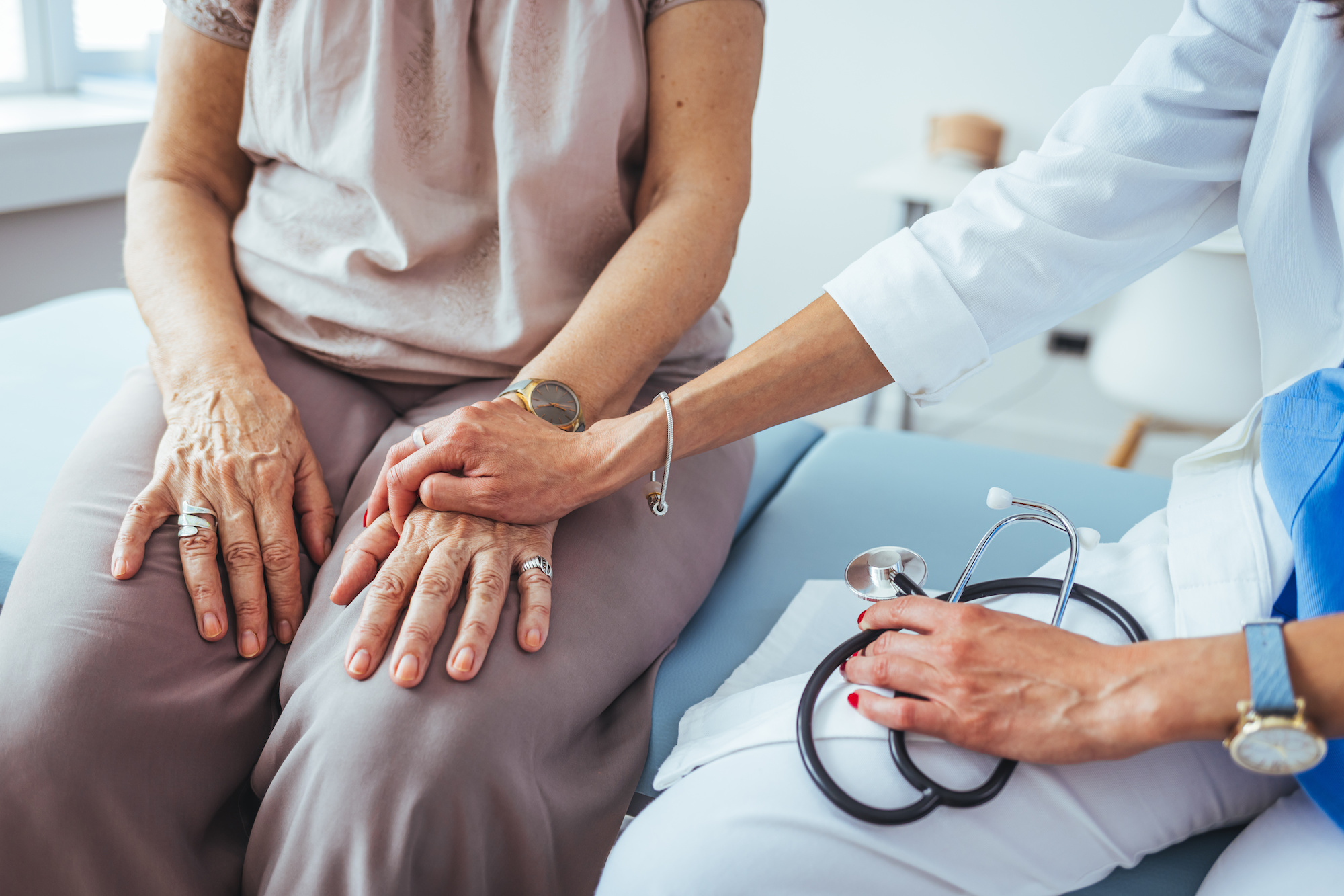 Cropped shot of a female doctor hold her senior patient's hand. Giving Support. Doctor helping old patient with Alzheimer's disease. Female carer holding hands of senior woman.